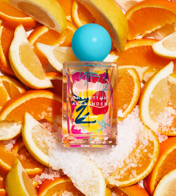 Christian Alexander perfume bottle surrounded by sliced oranges and lemons on a bed of salt.